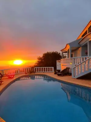 a swimming pool with a sunset in the background at Villa Quinta da Violeta in Loulé