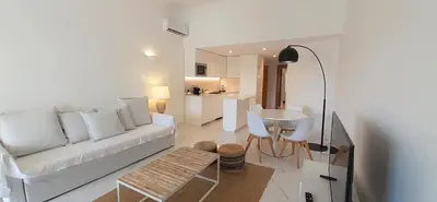 a white living room with a couch and a tv at Quinta do Lago Beach House in Quinta do Lago