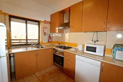 a kitchen with wooden cabinets and a white microwave at Marbel Sol - Clever Details in Vilamoura