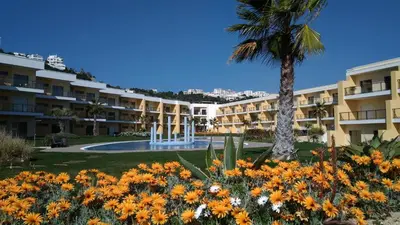 a large building with a palm tree and flowers at Apartamento luxo e sossego in Albufeira
