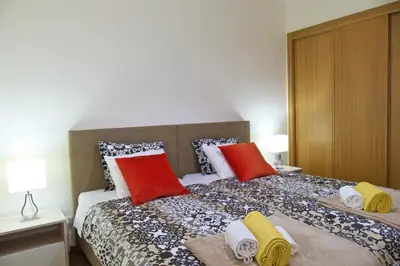 a bedroom with a bed with red and yellow pillows at Apartamento luxo e sossego in Albufeira