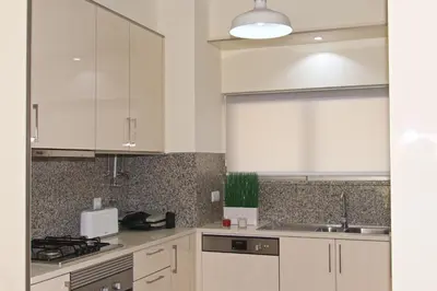 a kitchen with white cabinets and a sink at Apartamento luxo e sossego in Albufeira