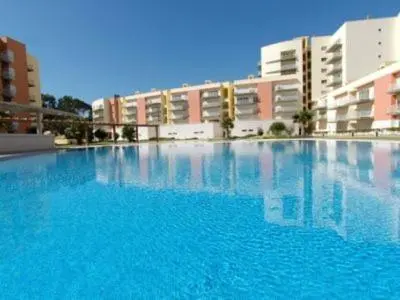 a large pool of blue water in front of buildings at Apartamento Vilamoura in Quarteira