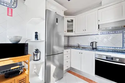 a kitchen with white cabinets and a stainless steel refrigerator at Penthouse Sea View by Albufeira Holidays in Albufeira