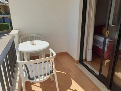 a white table and a chair on a balcony at Apartment on The Strip Albufeira in Albufeira