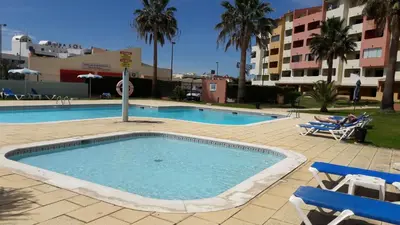 a large swimming pool with two chairs and a person sitting in avisorvisorvisor at Apartamento Bela Vista in Albufeira