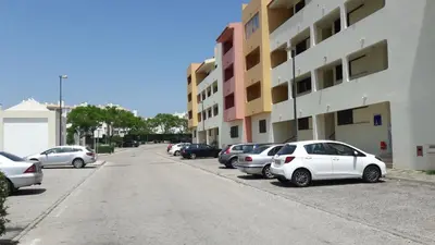 a row of parked cars parked next to a building at Apartamento Bela Vista in Albufeira