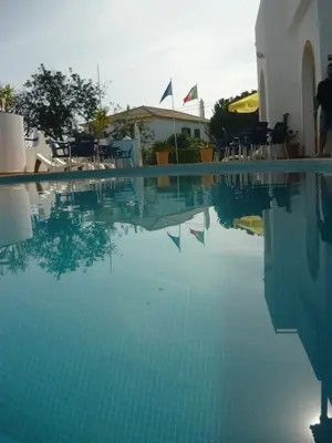 a pool of water with chairs and a building at Agua Marinha ROSA- Hotel in Albufeira