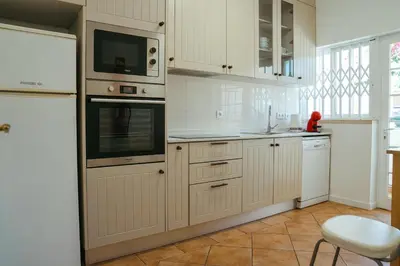 a kitchen with white cabinets and white appliances at Moradias Villas Rufino in Albufeira