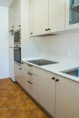 a white kitchen with white cabinets and a sink at Moradias Villas Rufino in Albufeira