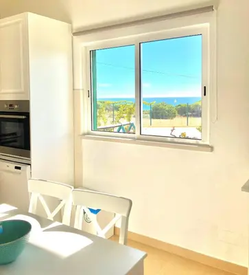 a kitchen with a window and a table and chairs at Moradias Villas Rufino in Albufeira