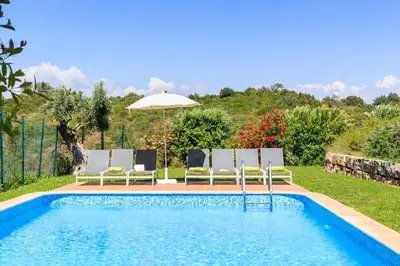a swimming pool with two chairs and an umbrella at Eden Villas & Apartments in Albufeira