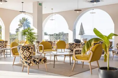 a dining room with chairs and tables and a plant at Eden Villas & Apartments in Albufeira
