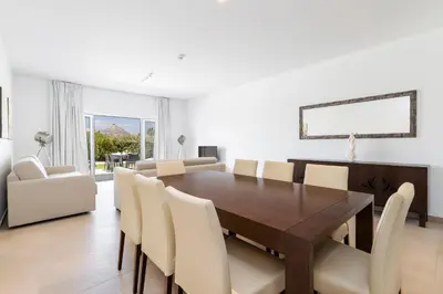 a dining room with a wooden table and white chairs at Eden Villas & Apartments in Albufeira