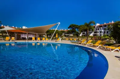 a large swimming pool with chairs and a building at Boa Vida in Quarteira