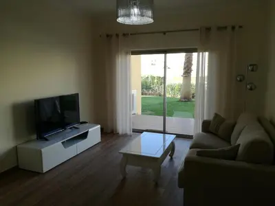 a living room with a couch and a flat screen tv at Apartamento O Jardins da Marina in Albufeira
