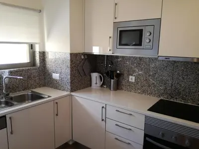 a kitchen with white cabinets and a sink and a microwave at Apartamento O Jardins da Marina in Albufeira