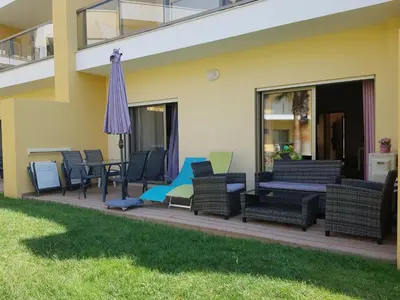 a deck with chairs and an umbrella on a house at Apartamento O Jardins da Marina in Albufeira