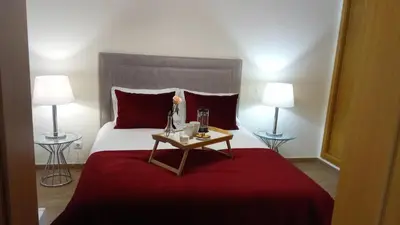 a bedroom with a bed with a red blanket and two lamps at Apartamento O Jardins da Marina in Albufeira