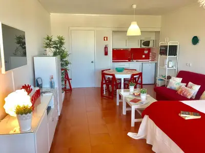 a living room with a red couch and a kitchen at Romantic Studio By Ethnic Ocean in Vilamoura