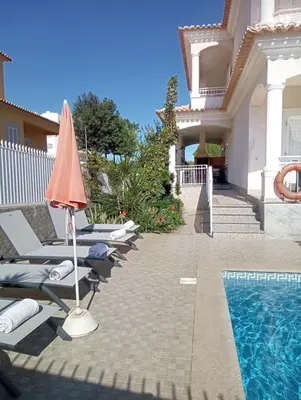a villa with a swimming pool with lounge chairs and an umbrella at Vivenda Luz - Jacuzzi & Swimming Pool in Albufeira