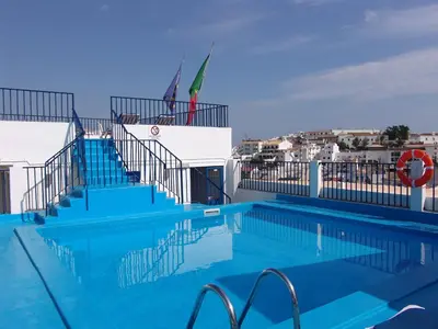 a large swimming pool with stairs and a building at Apartamentos Turisticos Regina in Albufeira