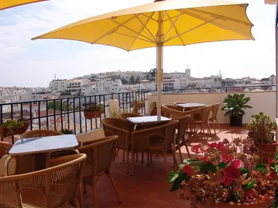 a patio with tables and chairs and a yellow umbrella at Apartamentos Turisticos Regina in Albufeira