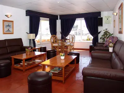 a living room with couches and a table and chairs at Apartamentos Turisticos Regina in Albufeira
