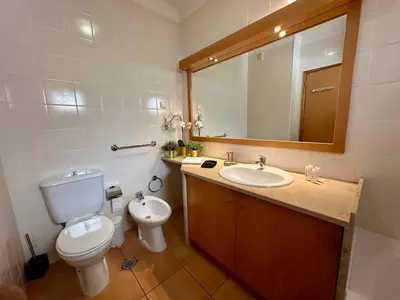 a bathroom with a toilet and a sink and a mirror at Monteverde Kulle by FHR piscina & parking in Vilamoura