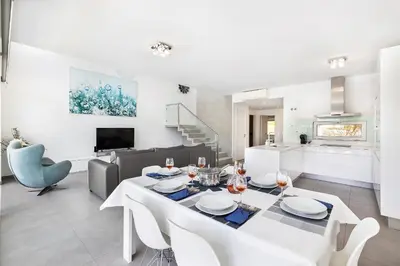a dining room and living room with a white table and chairs at Design Villa Pascoal in Albufeira