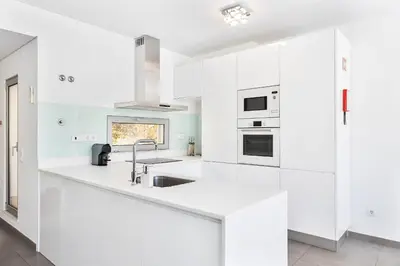 a white kitchen with white cabinets and a sink at Design Villa Pascoal in Albufeira
