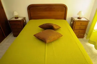 a yellow bed with two pillows and two night stands at Villa V4 com Piscina Privada a 400 metros da Praia in Albufeira