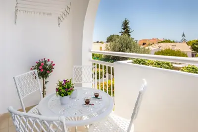 a white table and chairs on a balcony with flowers at Camilla apartment in Albufeira