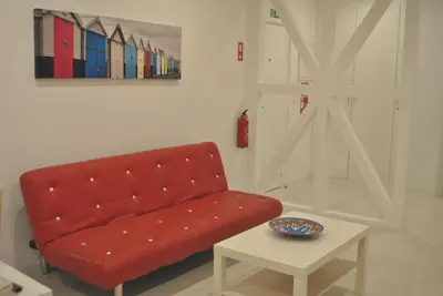 a red couch in a living room with a table at Stay Inn Albufeira - 303B Apartment in Albufeira