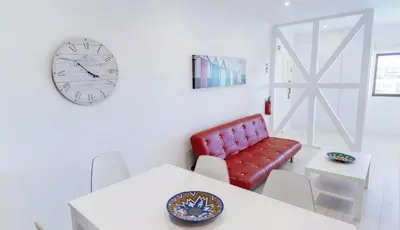 a dining room with a red chair and a clock at Stay Inn Albufeira - 303B Apartment in Albufeira