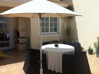a table with an umbrella in a room at Holiday Duplex Alto dos Salgados in Albufeira