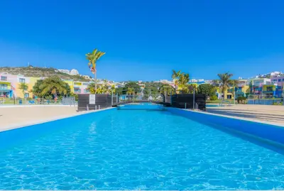a swimming pool in a resort with palm trees and buildings at Apartamentos da Orada by Garvetur in Albufeira
