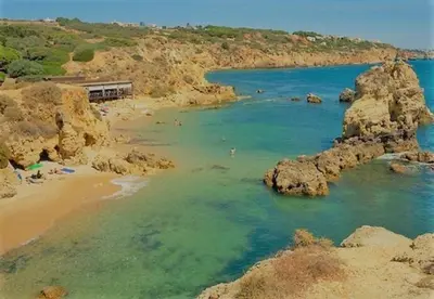 a beach with rocks and people in the water at The Albufeira Concierge - Modern Salgados in Albufeira