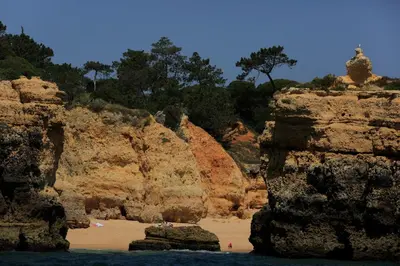 a group of people standing on a beach between rocks at Casa Laranjinha in Albufeira