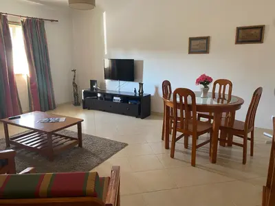 a living room with a table and chairs and a tv at Nice apartment near Faro's airport in Faro