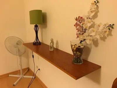 a vase of flowers on a wooden shelf with a fan at Nice apartment near Faro's airport in Faro