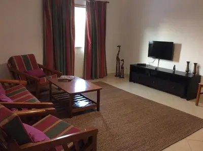a living room with a tv and chairs and a table at Nice apartment near Faro's airport in Faro