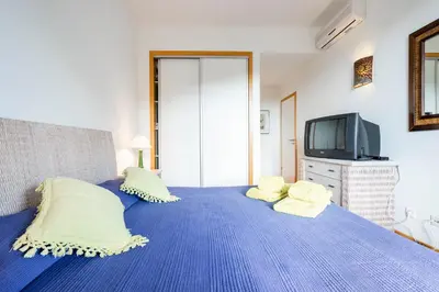 a bedroom with a blue bed with pillows and a tv at Golf Residence Apartment in Vilamoura