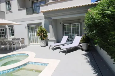 a patio with two chairs and a swimming pool at Charming Exceptional Golf Villa in Algarve in Faro