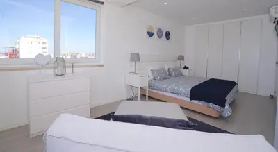 a white bedroom with a bed and a window at Paradise Quarteira in Quarteira