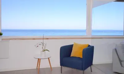 a blue chair in a room with a view of the ocean at Paradise Quarteira in Quarteira