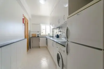 a white kitchen with a sink and a refrigerator at Albufeira Centrally Located Apartment with Pool View in Albufeira
