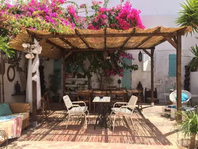 a patio with a table and chairs and flowers at Casa dos Arcos - Charm Guesthouse in Albufeira