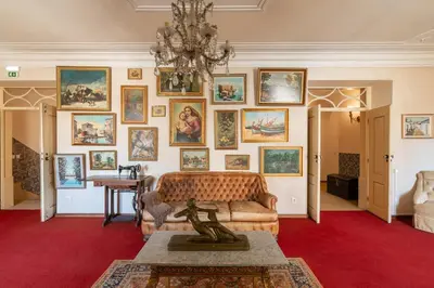 a living room with a couch and a wall of paintings at Casa dos Arcos - Charm Guesthouse in Albufeira