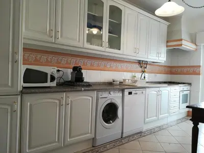 a kitchen with white cabinets and a washer and dryer at Porque Você Merece in Quarteira